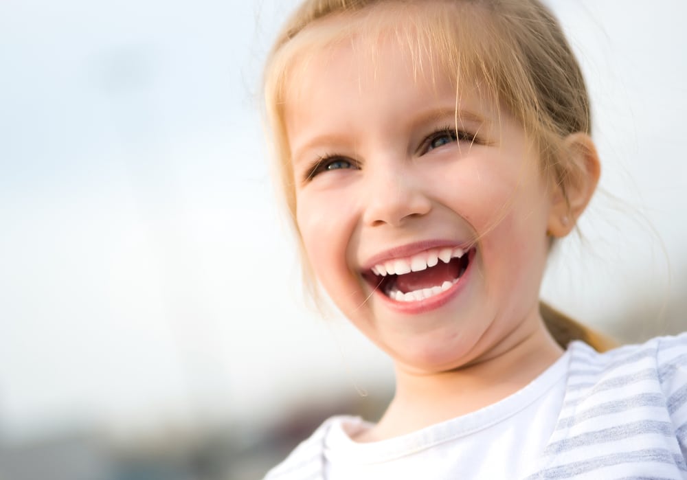 Smiling young girl enjoys her time outside following treatment to reduce her ear infections in Austin.