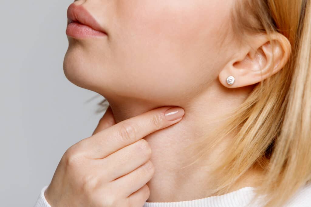 Woman grabs her throat which is sore after symptoms of allergies
