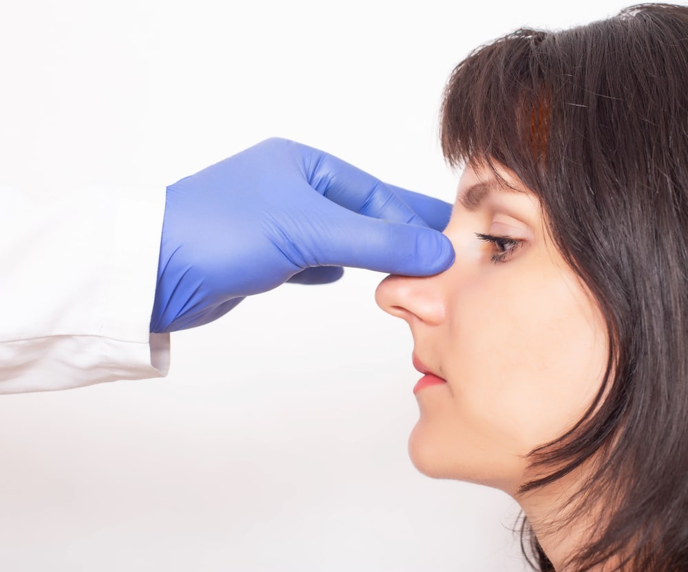 Woman has her nose examined by a gloved doctor who specializes in septoplasty in Austin, TX.