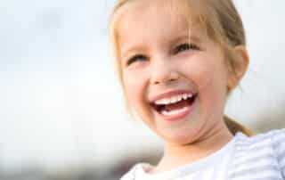 Smiling young girl enjoys her time outside following treatment to reduce her ear infections in Austin.